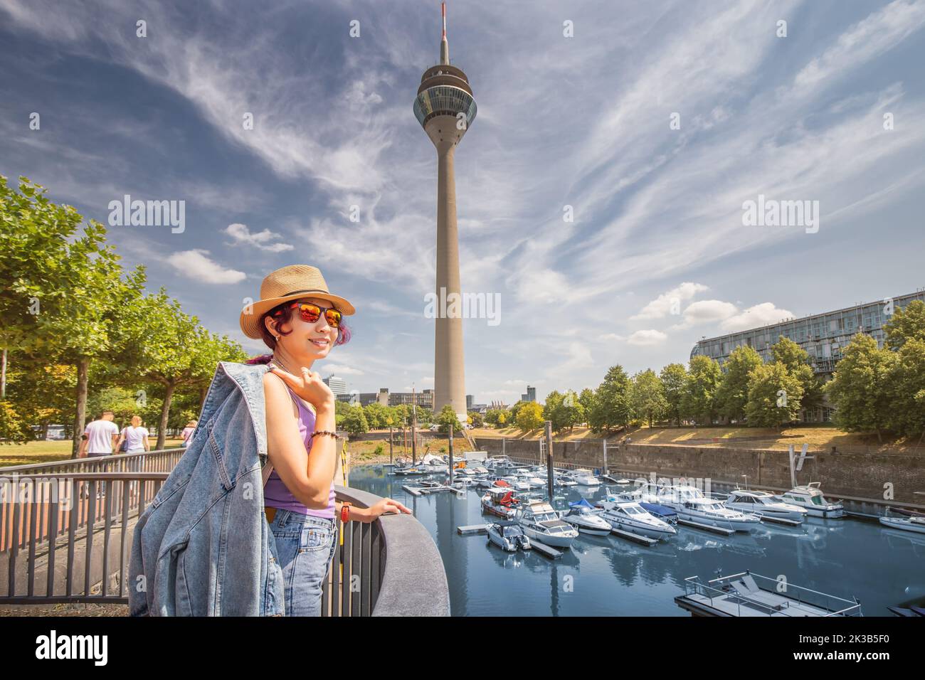Happy girl traveler enjoys a beautiful view in the Media Bay harbor and marina with TV-tower during a tourist trip or a student education in Dusseldor Stock Photo