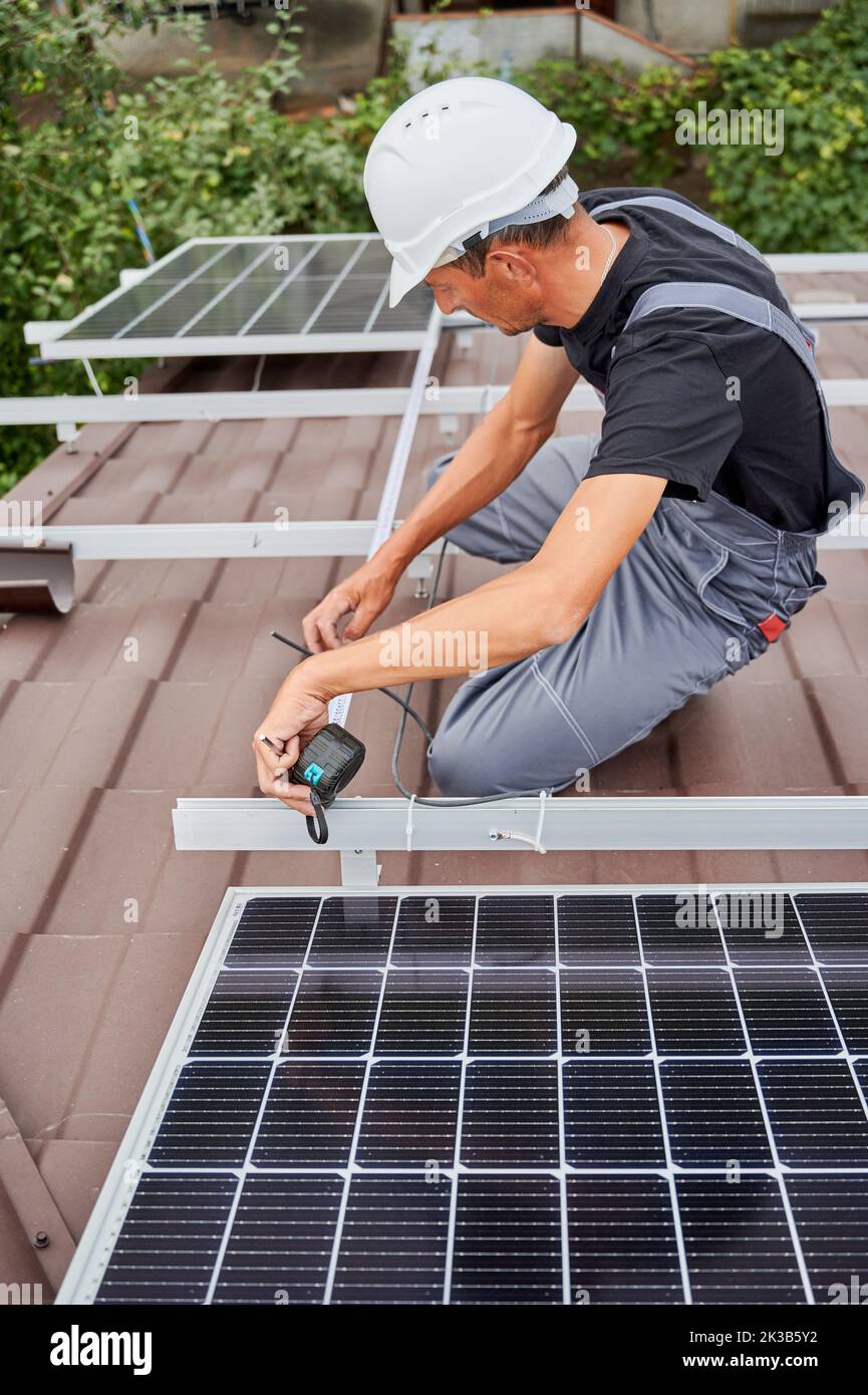 Man measuring photovoltaic solar panels with tape measure. Male worker