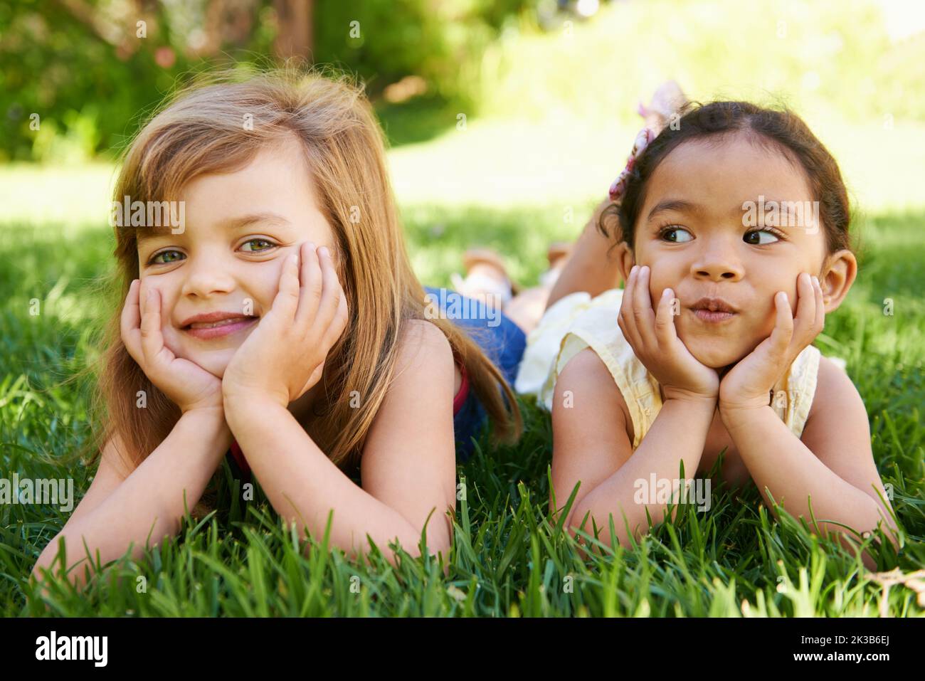 Wiling away the summer days together. two adorable little girls lying next to each other on the grass. Stock Photo