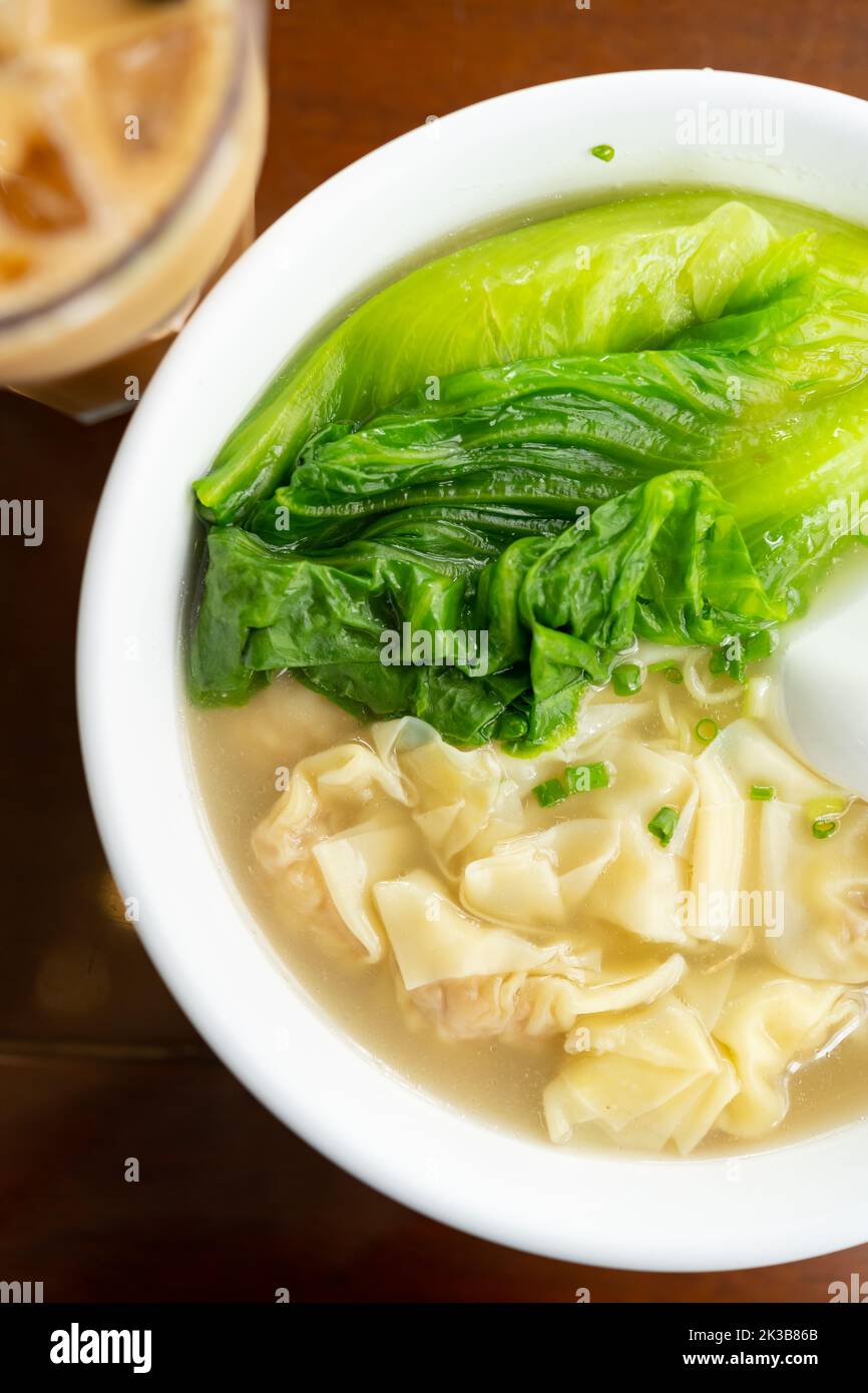 bowl of wontons with cup of iced milktea at vertical composition Stock Photo