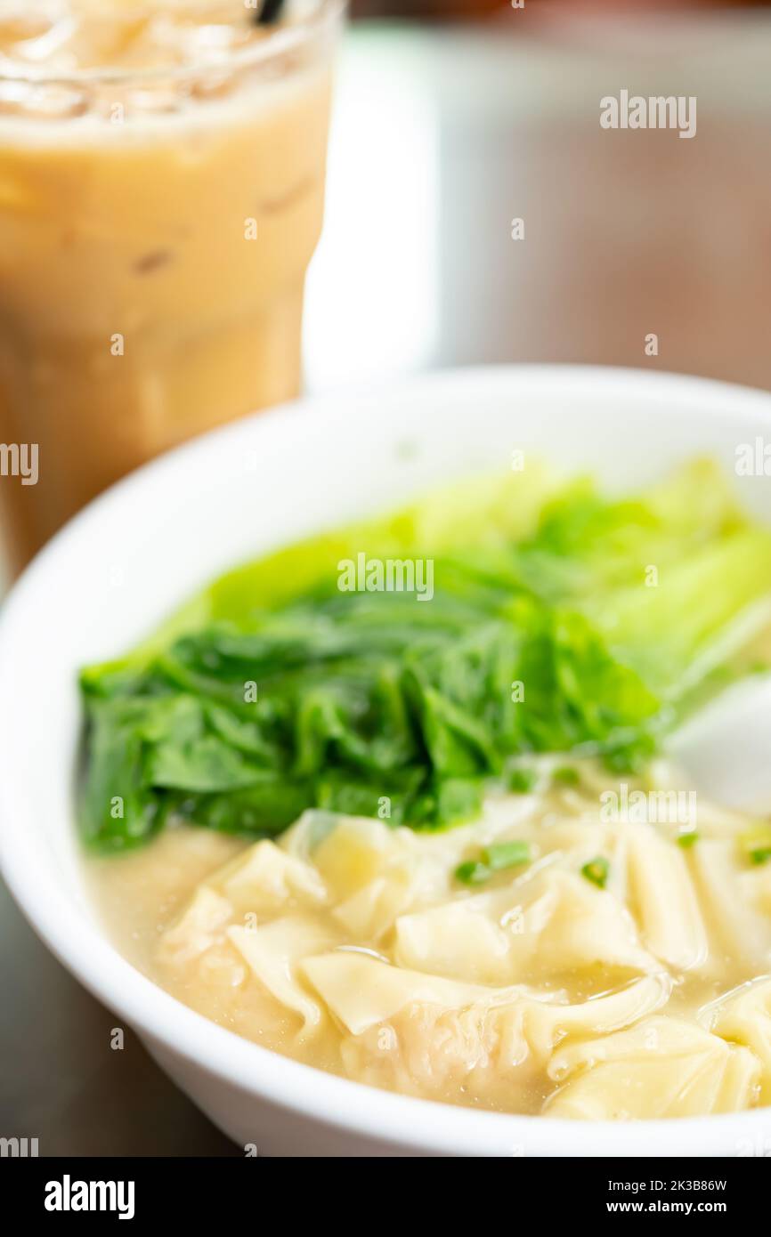 angle view bowl of wontons with cup of iced milktea at vertical composition Stock Photo