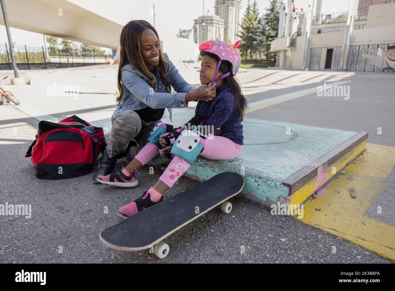Mother and daughter putting on skateboard safety equipment Stock Photo