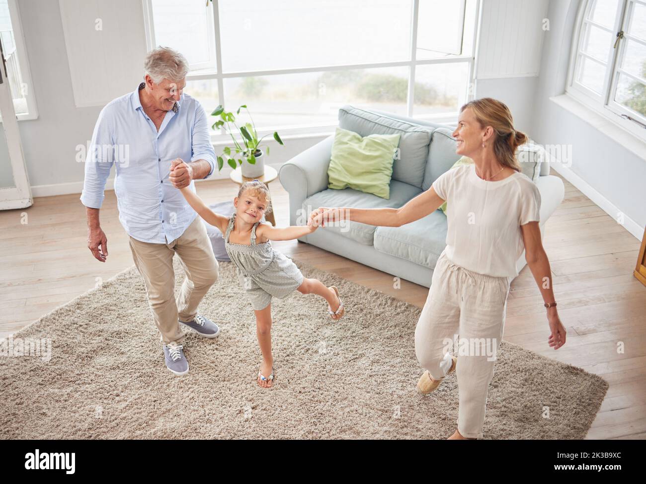 Family or grandparents dancing with child in living room for wellness, healthy body movement and growth development in retirement lifestyle. Happy Stock Photo