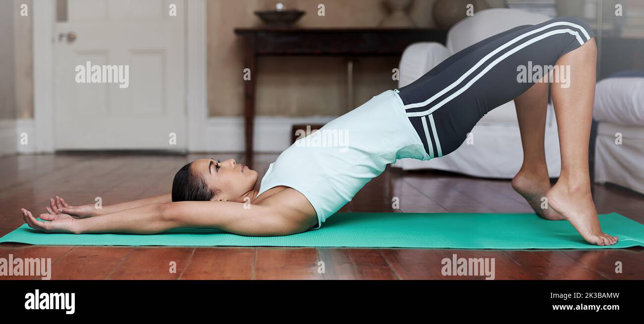 Yoga keeps her body flexible and strong. Full length shot of a young woman doing yoga at home. Stock Photo