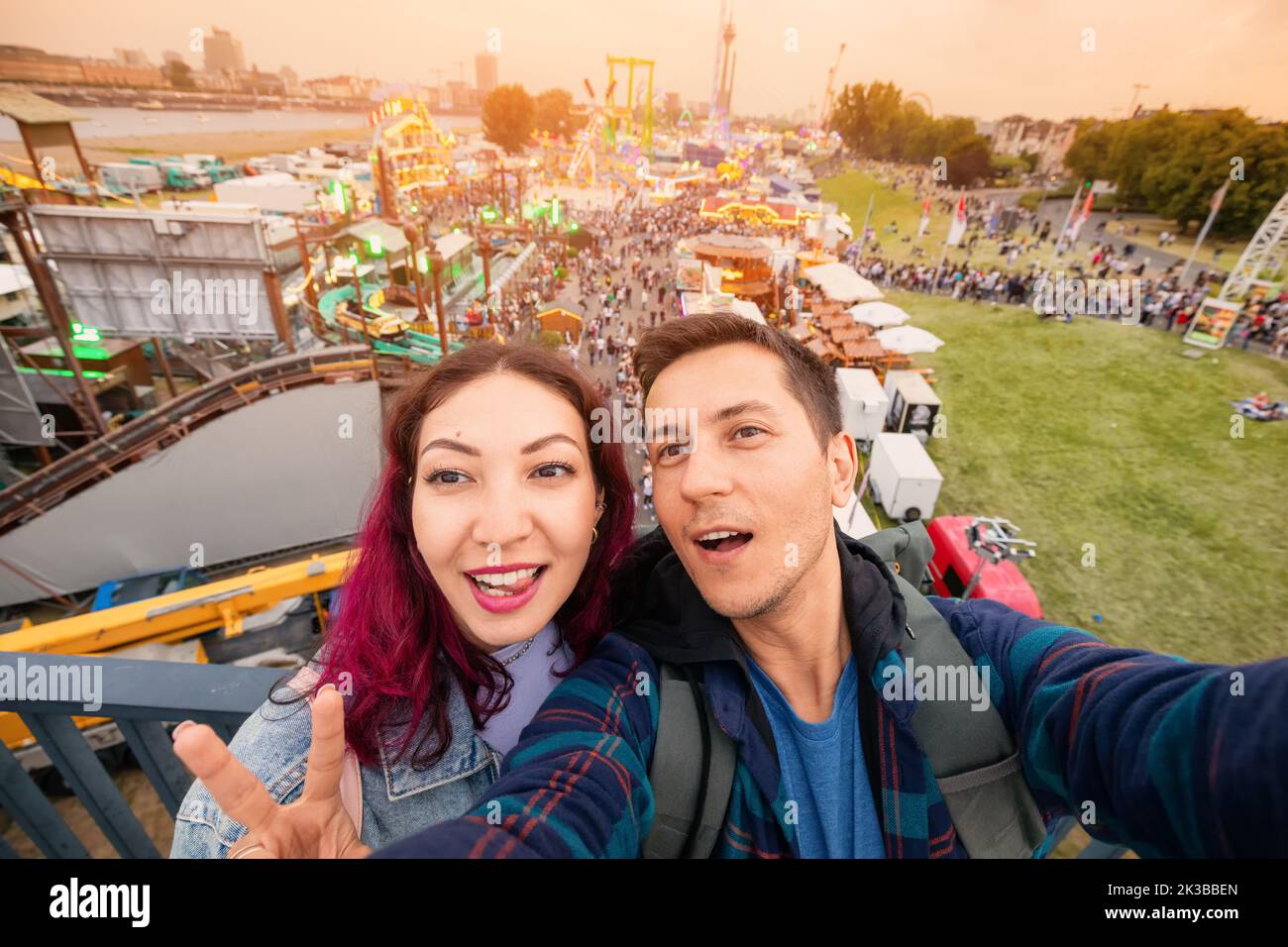 Tourist couple taking selfie photo at amusement fair and many eateries at a traditional festival on the park near bank of the Rhine river in Dusseldor Stock Photo