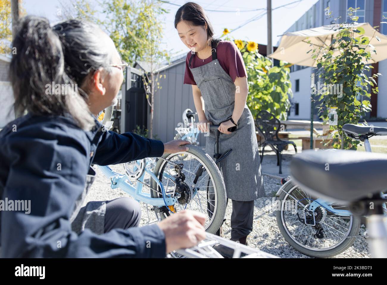 Young woman with Down Syndrome filling bicycle tire with air Stock