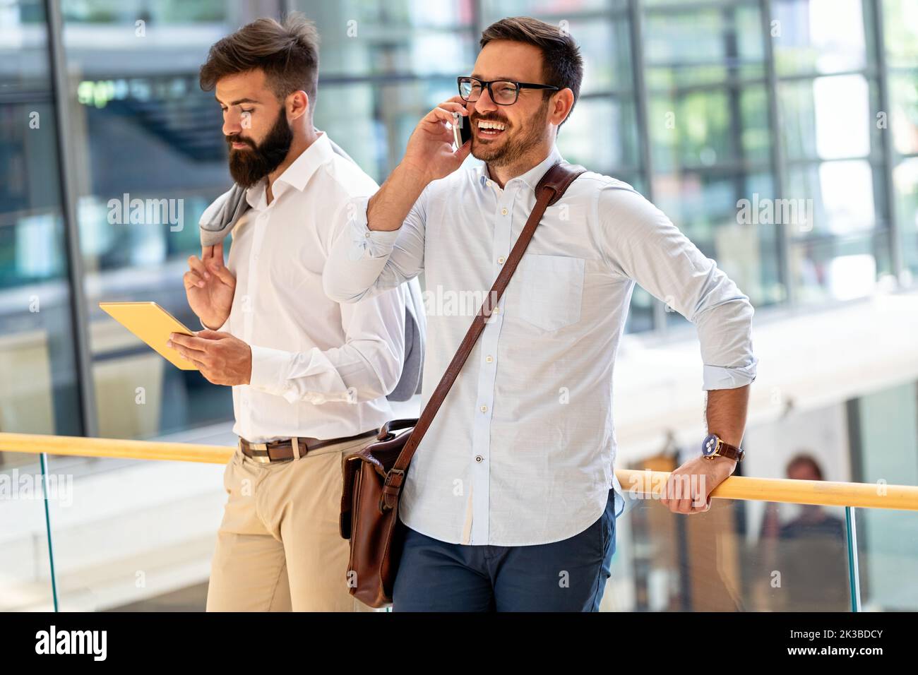 Handsome successful businessman using smartphone in front of office. Technology business concept. Stock Photo
