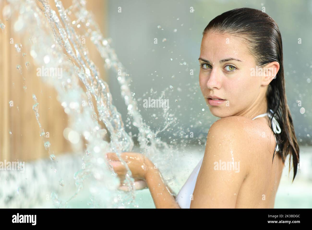 Beautiful woman bathing in spa looks at you under water jet Stock Photo
