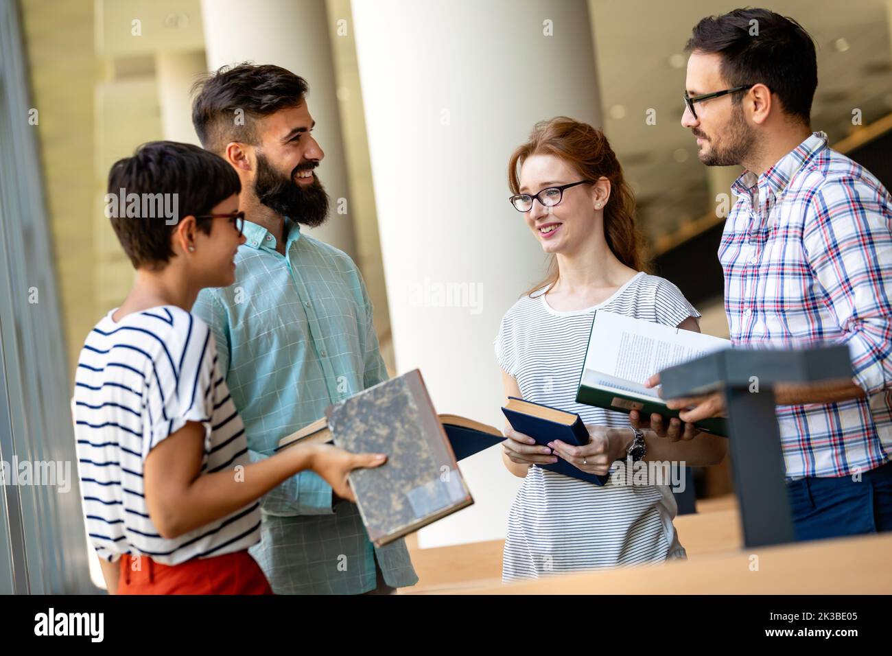 Happy university students studying with books in library. Group of multiracial people in college Stock Photo