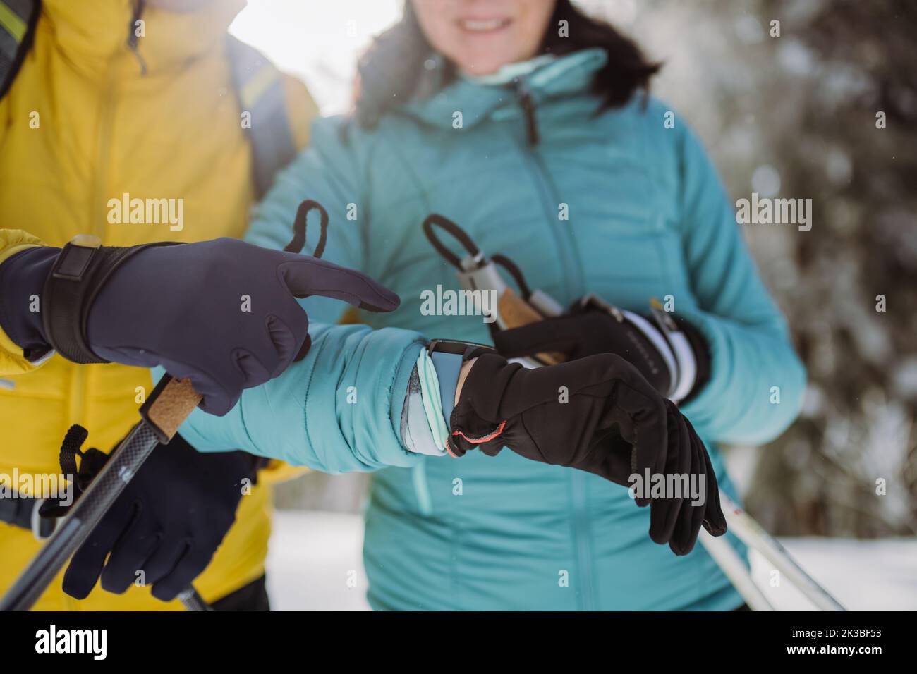 Close up of senior couple looking at smartwatch during winter skiing. Stock Photo