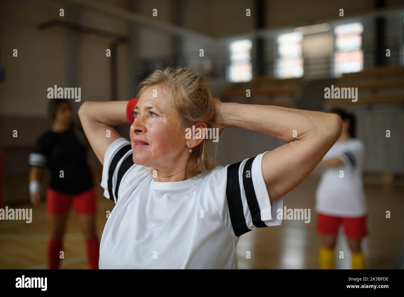 Senior woman stretching before basketball match in gym. Stock Photo