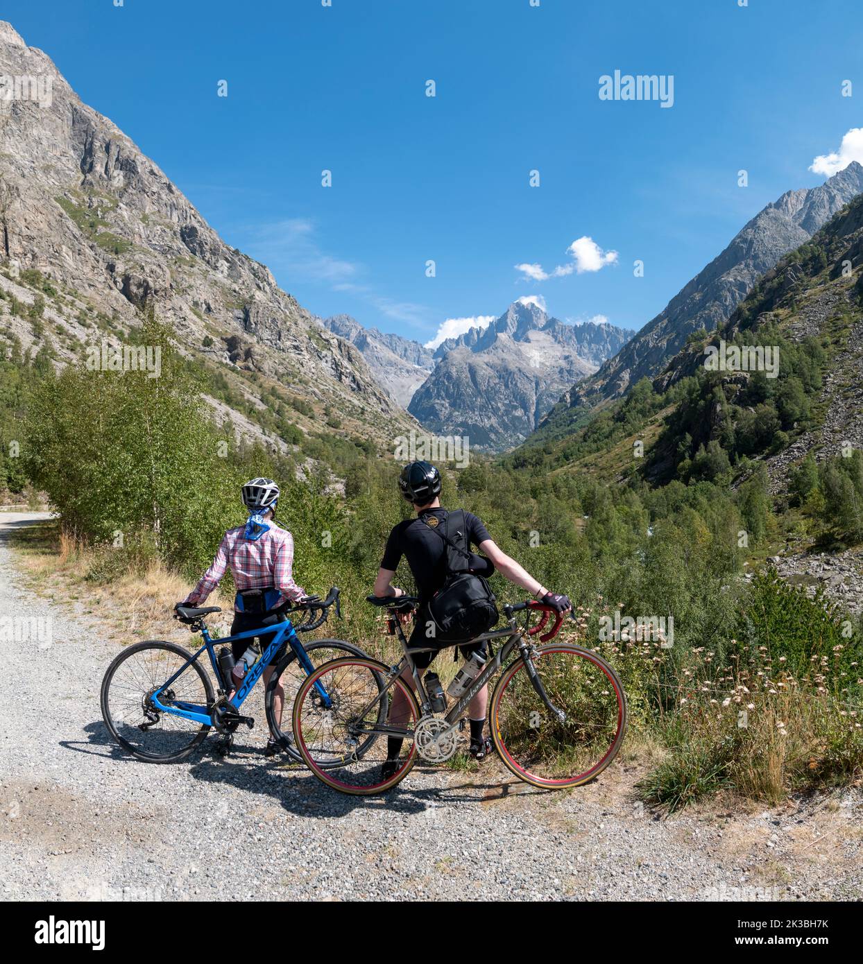 Two cyclists, Mother and son, take in the view in the high alpine valley above Saint-Christophe-en-Oisans, French Alps. Stock Photo