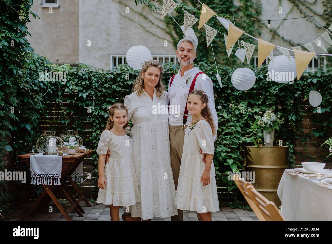 Mature bride and groom posing with their daughters at wedding reception outside in the backyard. Stock Photo