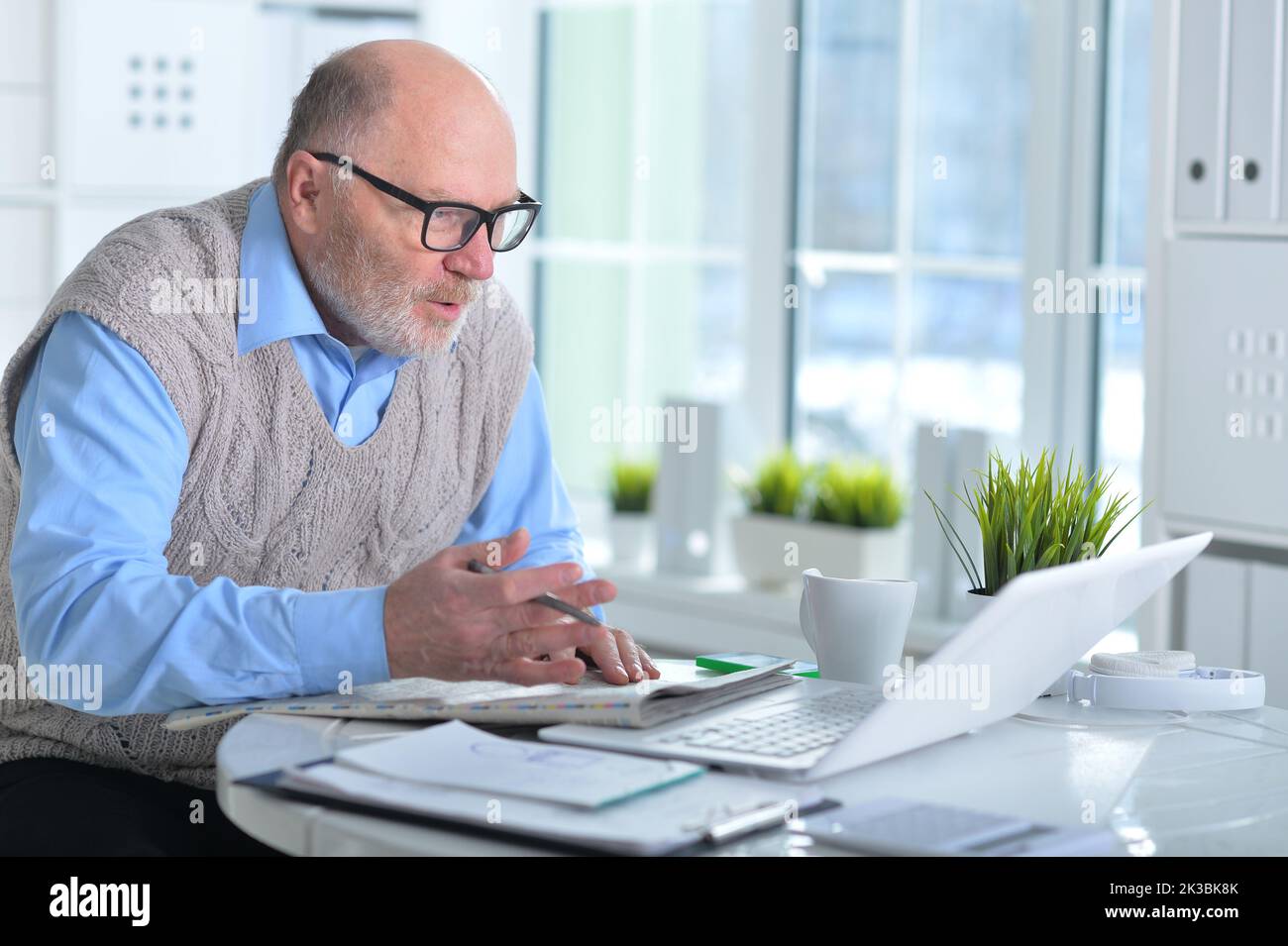 Close up portrait of emotional senior man reading newspaper at home Stock Photo