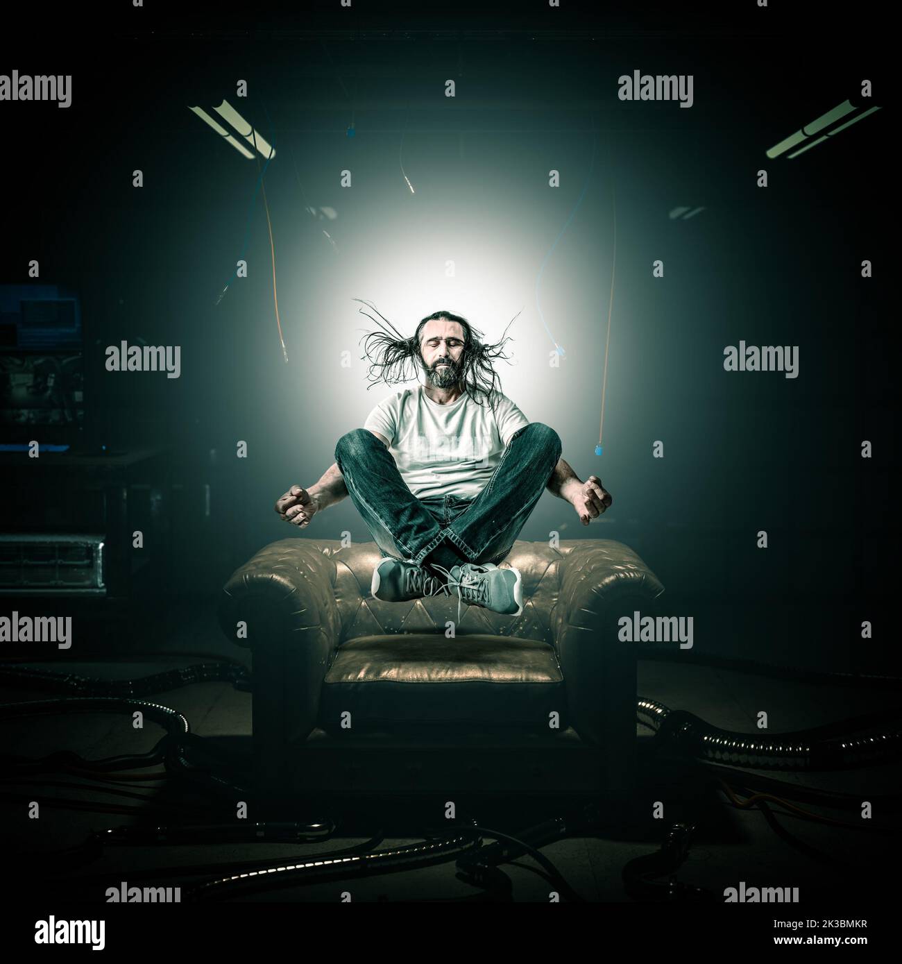 man in meditation floats in the air above an armchair, hacker room background Stock Photo