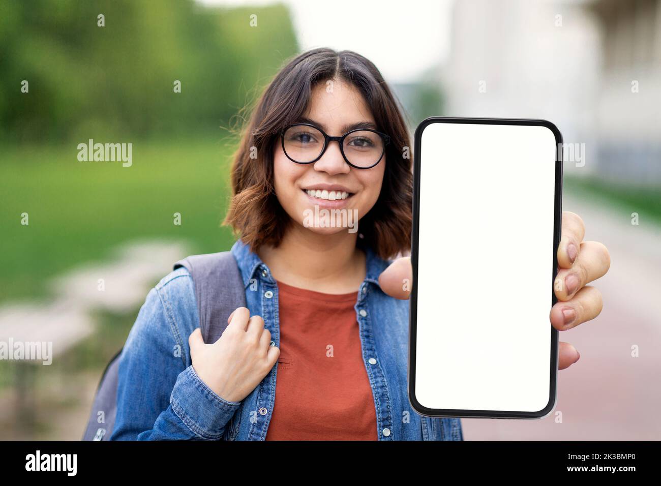 Educational Ad. Smiling Arab Female Student Demonstrating Big Blank Smartphone Outdoors Stock Photo