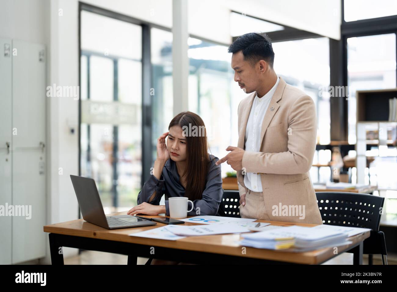 Asian team leader correcting offended employee at work. Mentor conflicts with student. Manager scolding worker for mistake or incompetence. Stock Photo