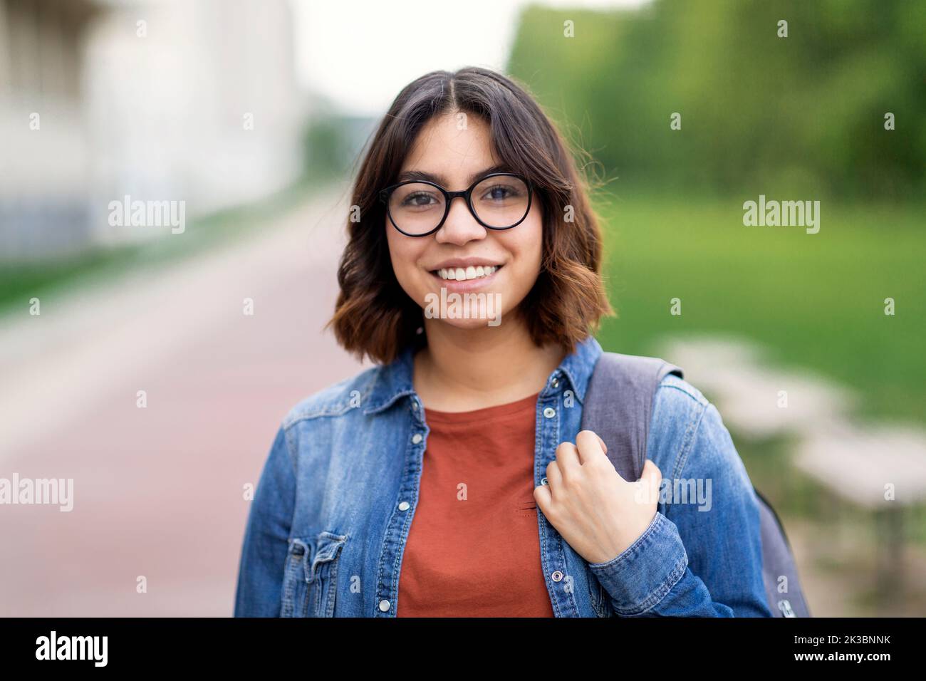 Portrait Of Smiling Beautiful Arab Female Student Wearing Eyeglasses Posing Outdoors Stock Photo
