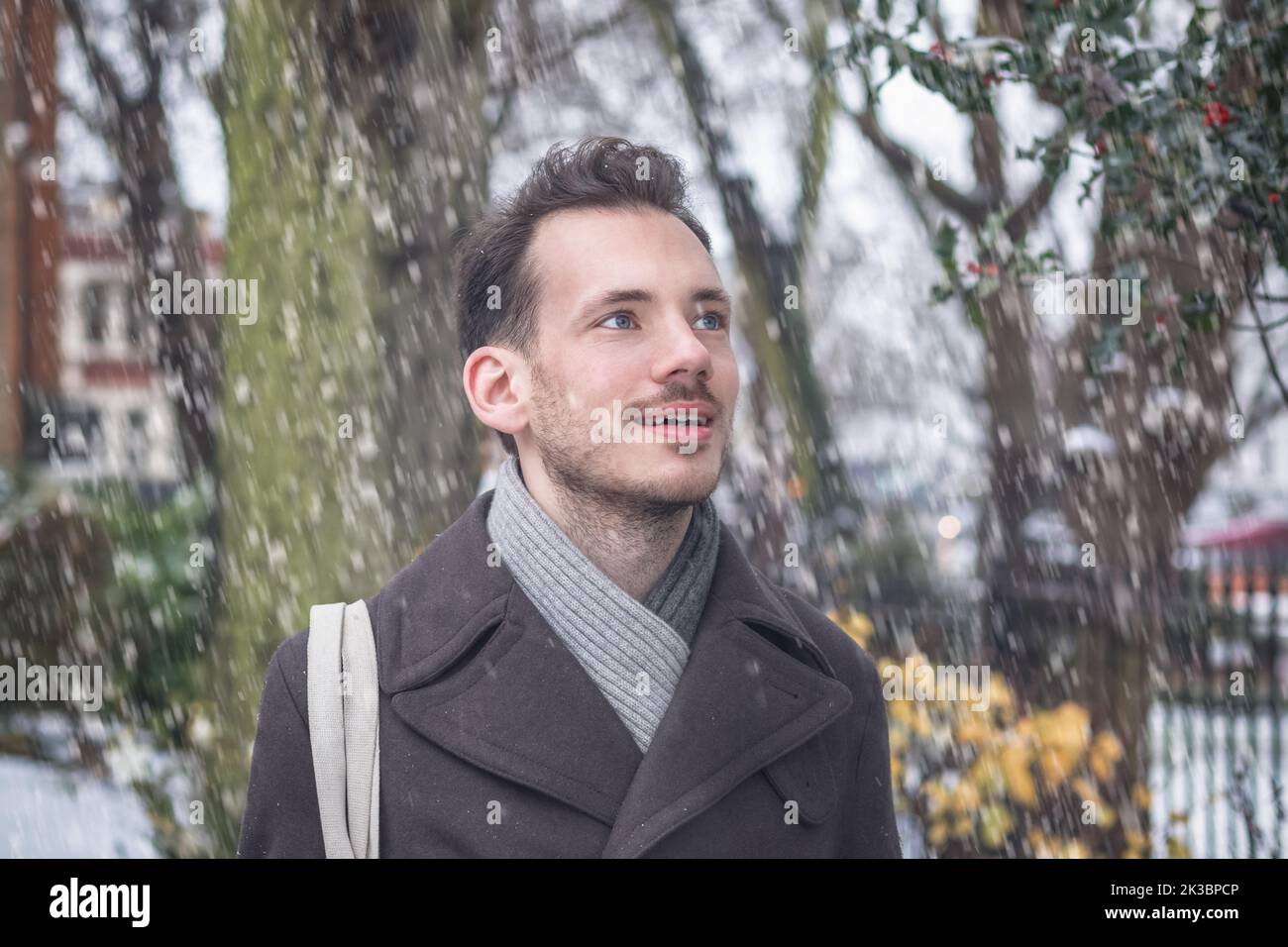 Portrait of young handsome man with beard smiling in winter snow Stock Photo