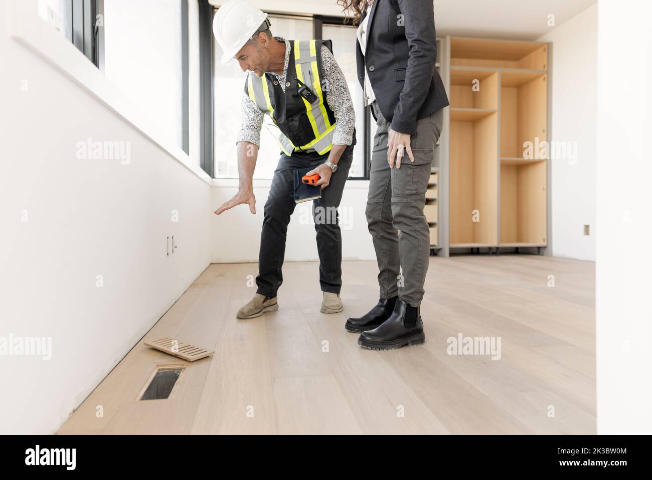 Architects looking at wood flooring in new house under construction Stock Photo