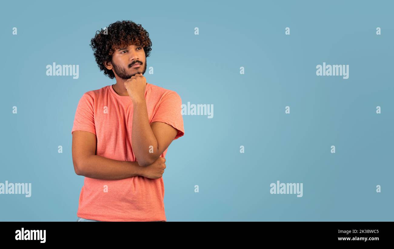 Pensive indian guy looking at copy space over blue background Stock Photo