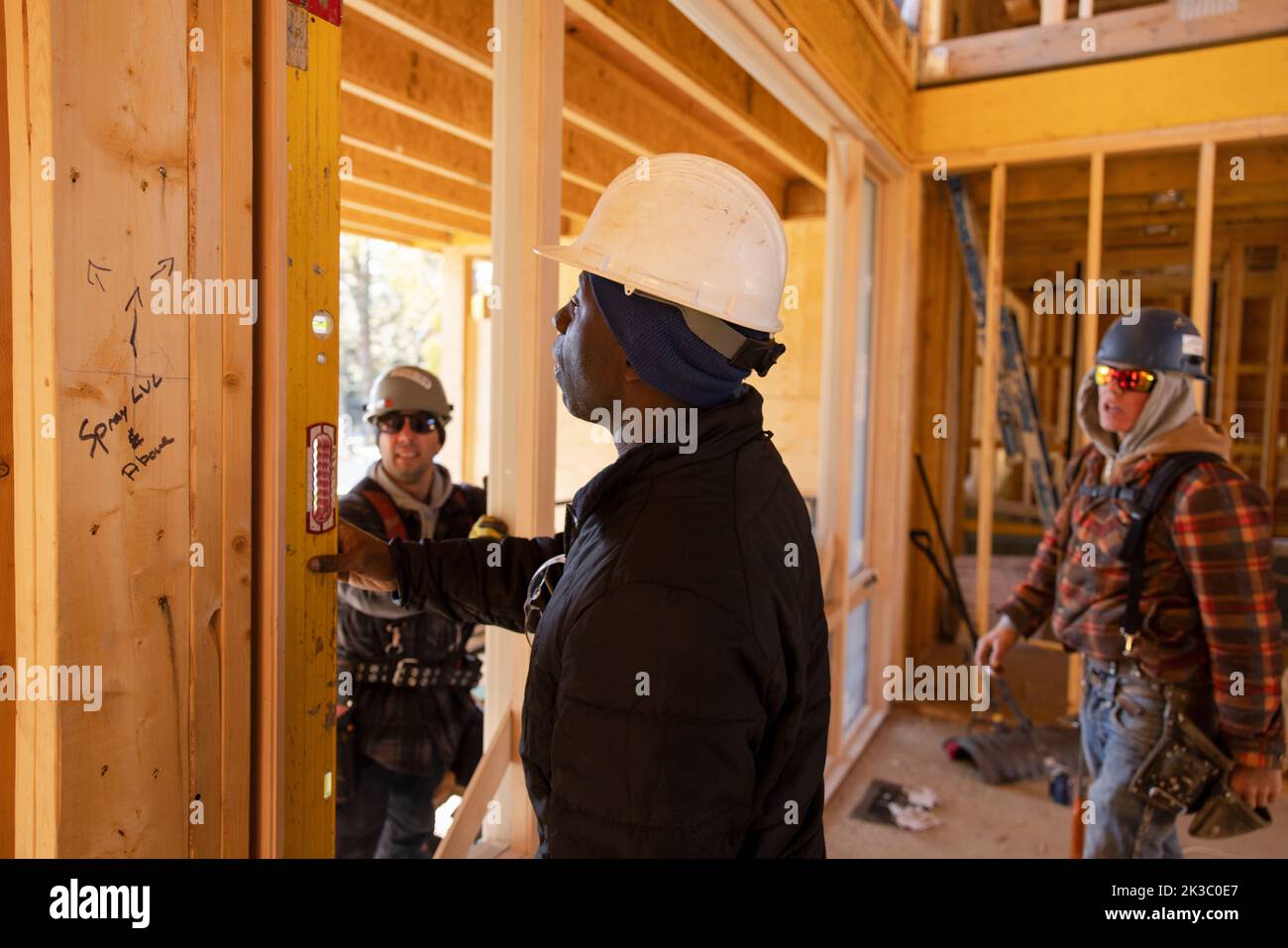 Male construction workers using level tool at construction site Stock