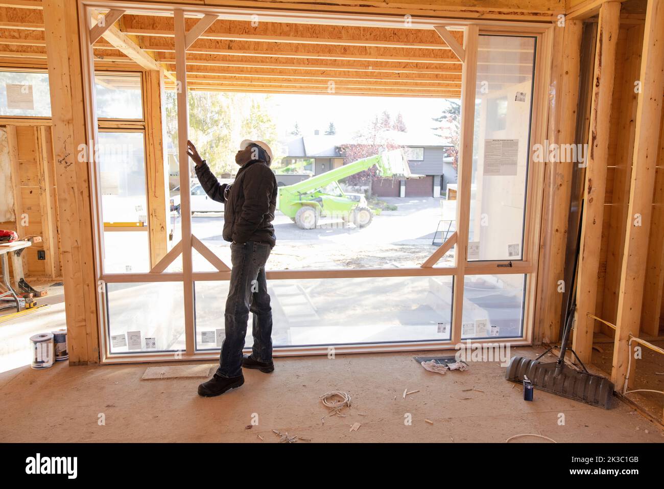 Male contractor inspecting wood frame house under construction Stock Photo