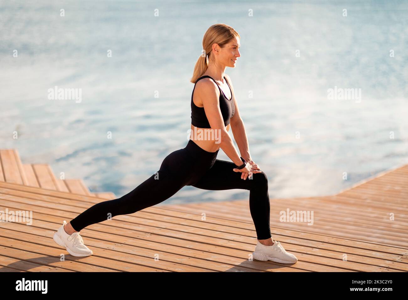 Athletic Middle Aged Female Stretching Leg Muscles While Training Outdoors Stock Photo