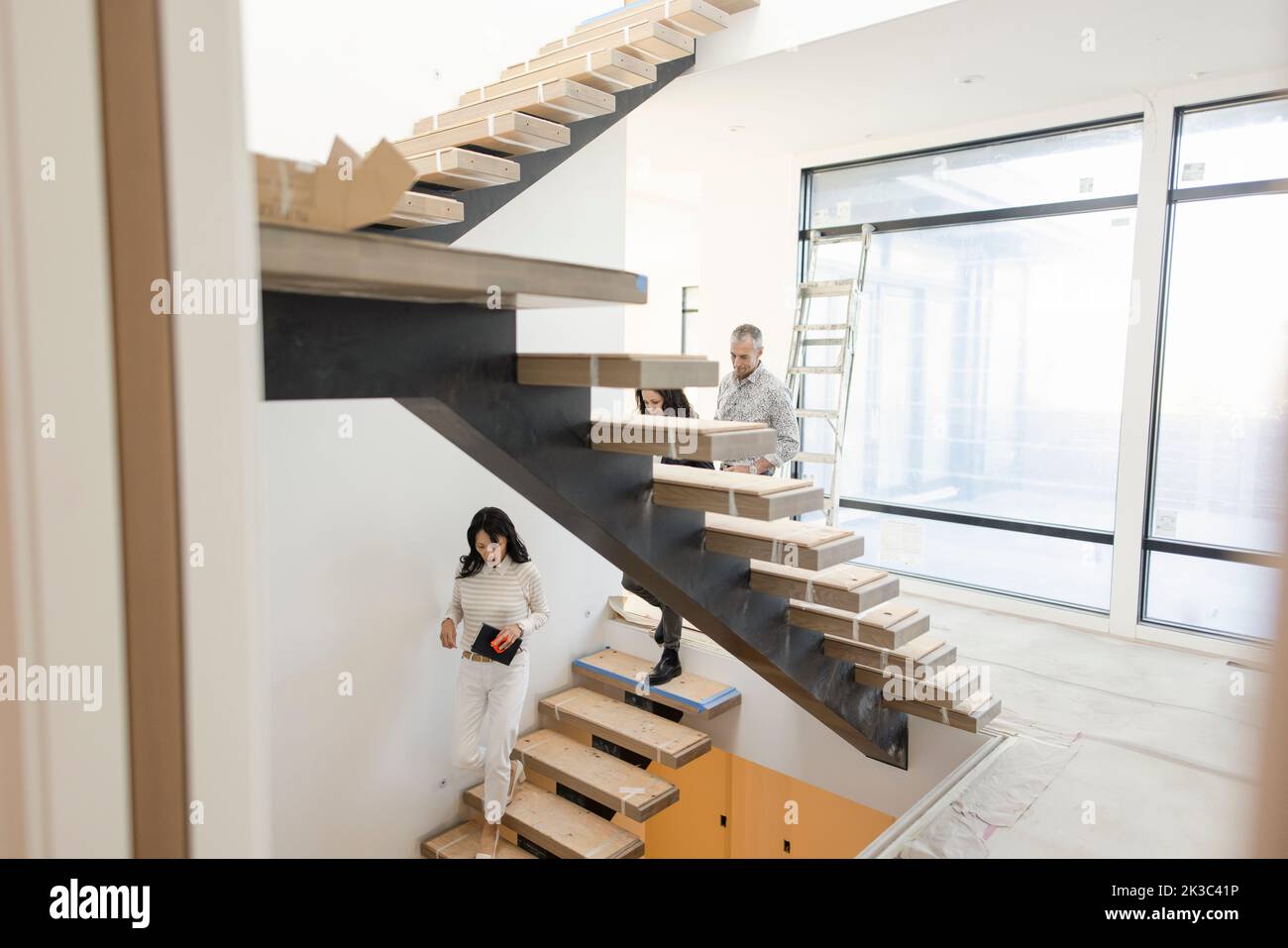 Interior designer and couple on modern steps in new house Stock Photo