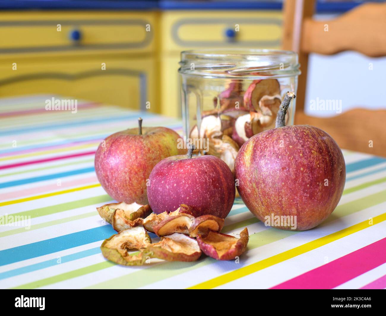 Dried apples and fresh apples placed on a wooden board, on a kitchen table Stock Photo