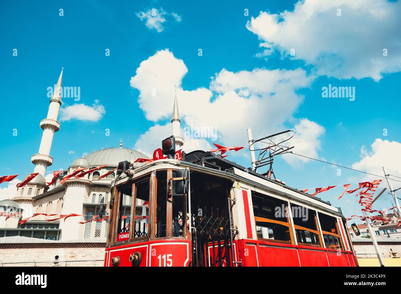 Taksim historical tram with Taksim Mosque in background, beautiful cityscape in Istanbul, blue cloudy sky, travel destination in Turkey, scenery retro train in sunny day, sightseeing place in Istanbul Stock Photo
