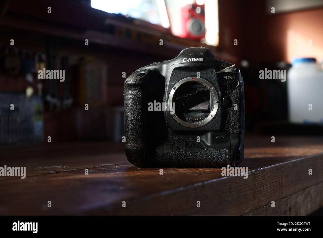 An old dusty, dirty and broken Canon EOS 1D digital camera on a bench in a garage. Stock Photo