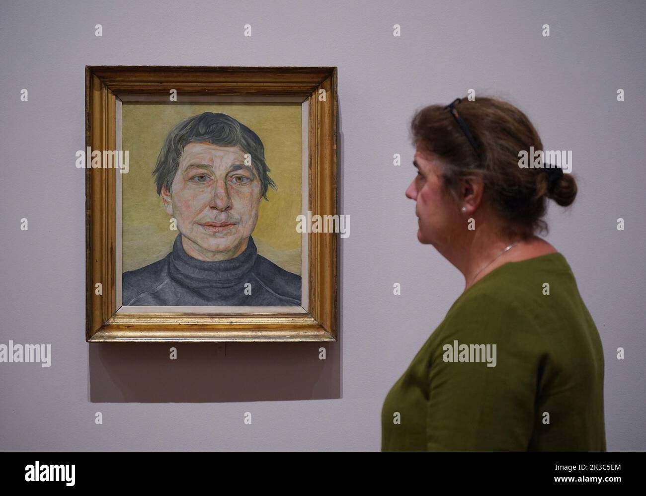 A gallery staff member poses next to a painting by Lucian Freud A