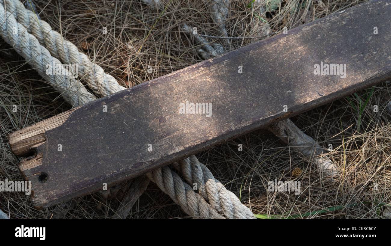 Wooden board and thick rope rope on dry grass Stock Photo