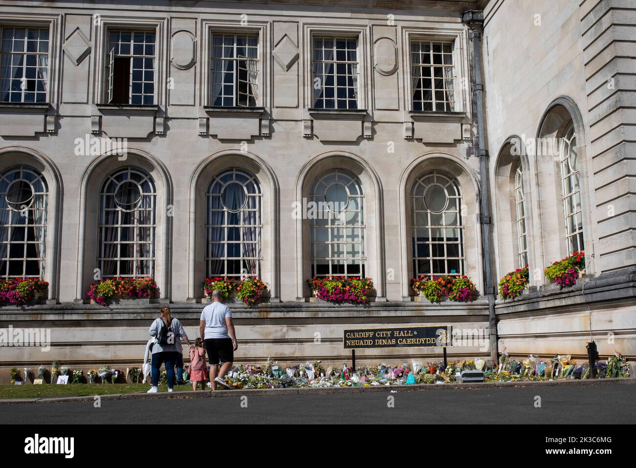 A family looks at a floral tribute to Queen Elizabeth II outside Cardiff City Hall, September 2022. Stock Photo