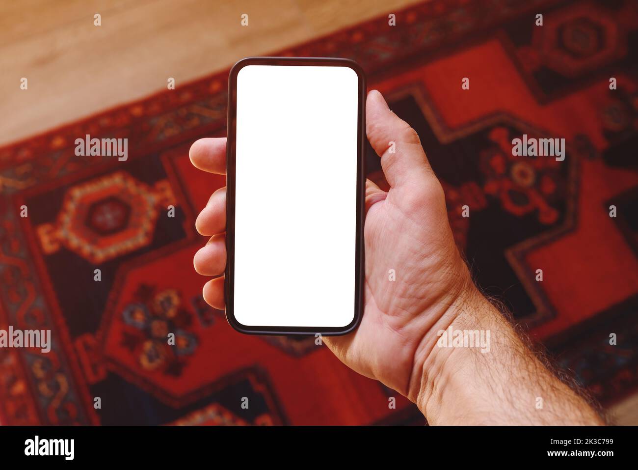 Mockup of of smartphone blank white touchscreen in male hand, man using mobile phone at home, selective focus Stock Photo