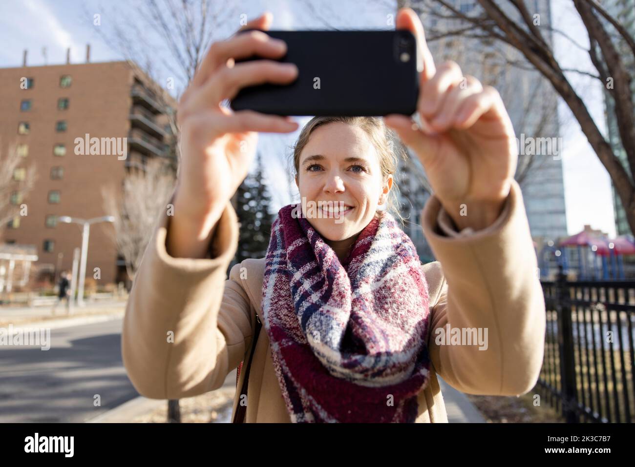 Happy young woman taking selfie on urban sidewalk Stock Photo - Alamy