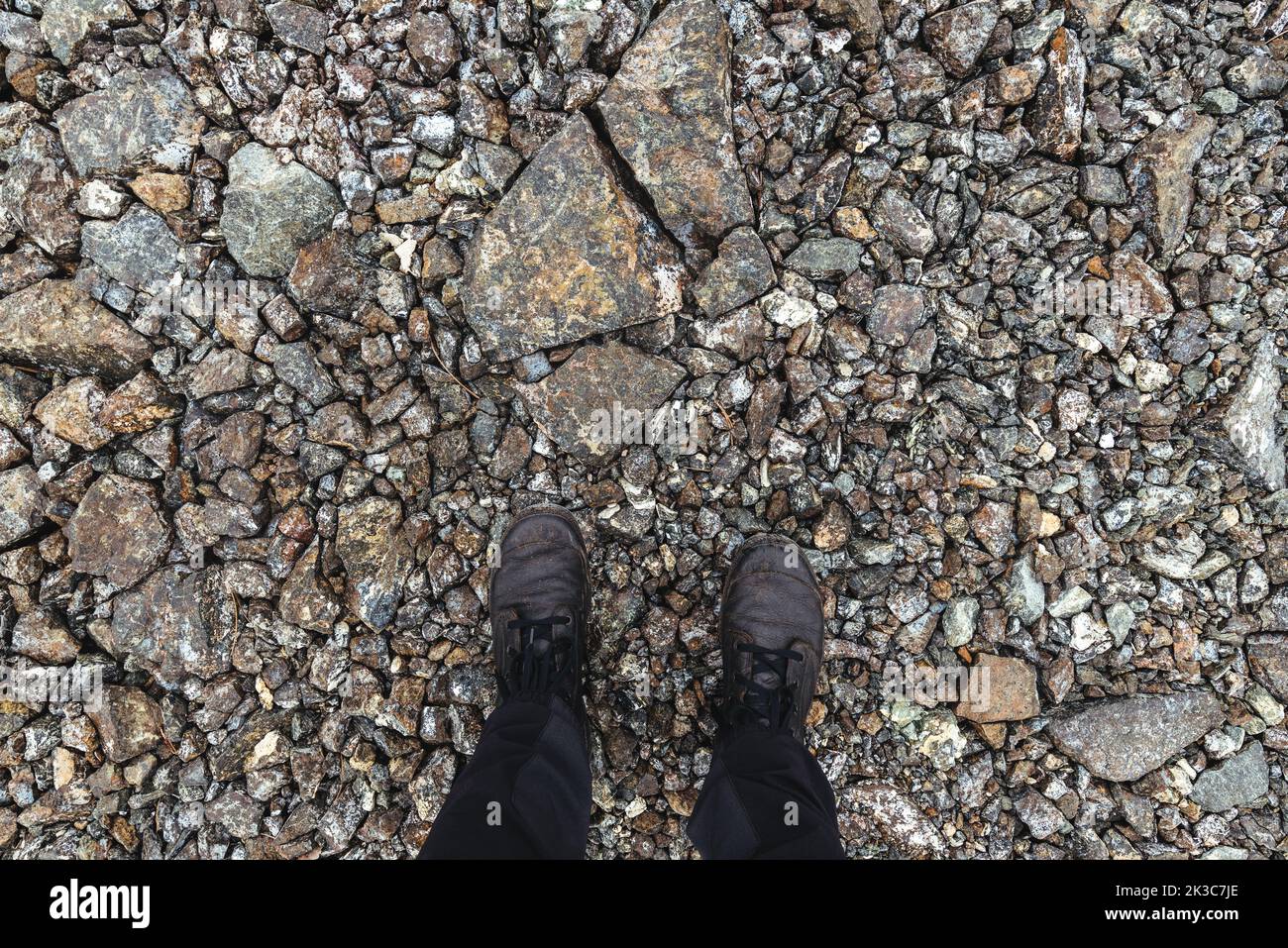 Worn boots on rough rocky footpath, directly above Stock Photo