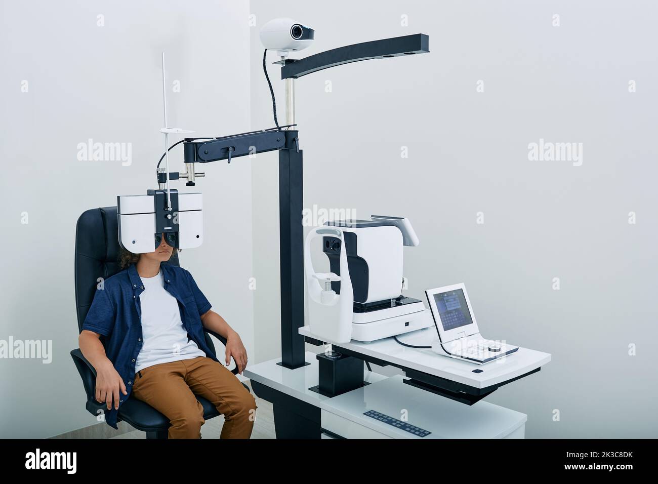 Boy has eye test in ophthalmological clinic looking through phoropter