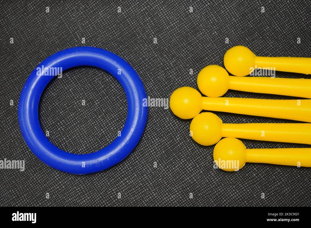 Concept with yellow and blue toy sticks and rings in front of black background. Colorful plastic ring and sticks. Yellow and blue. Stock Photo