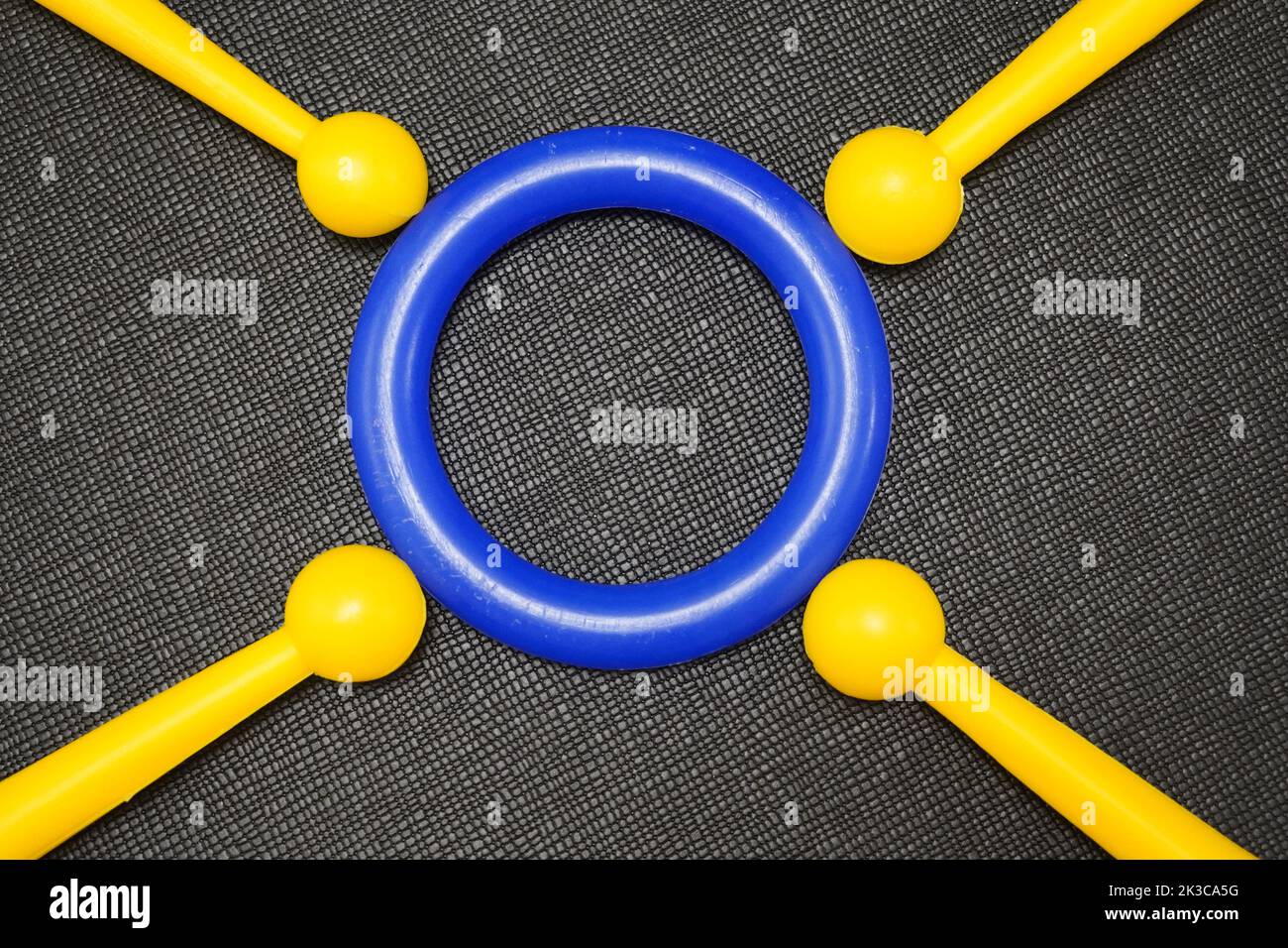 Concept with yellow and blue toy sticks and rings in front of black background. Colorful plastic ring and sticks. Yellow and blue. Stock Photo