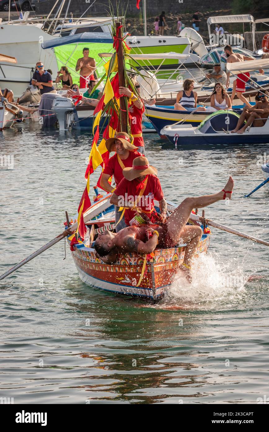 The annual festival of 'U Pisci a Mari' in the Sicilian village of Aci Trezza, near Catania. This takes place around the Feast of the Nativity of St John the Baptist, at the end of June. It represents a traditional fishing expedition for swordfish, which used to take place in the Strait of Messina. The part of the swordfish is played by a swimmer, who is repeatedly caught by the fishermen, bloodily sliced up but then somehow manages to escape. Eventually the 'swordfish' manages to overturn the boat. (Pouring fake blood over the 'swordfish') Stock Photo