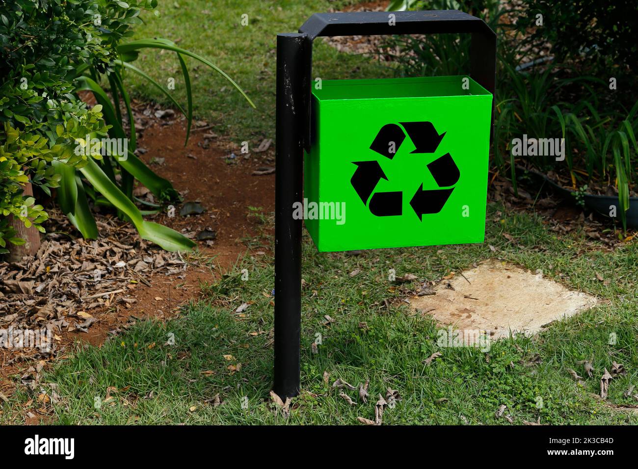 green metal trash can with recycling symbol in green public area and garden - garbage collection Stock Photo