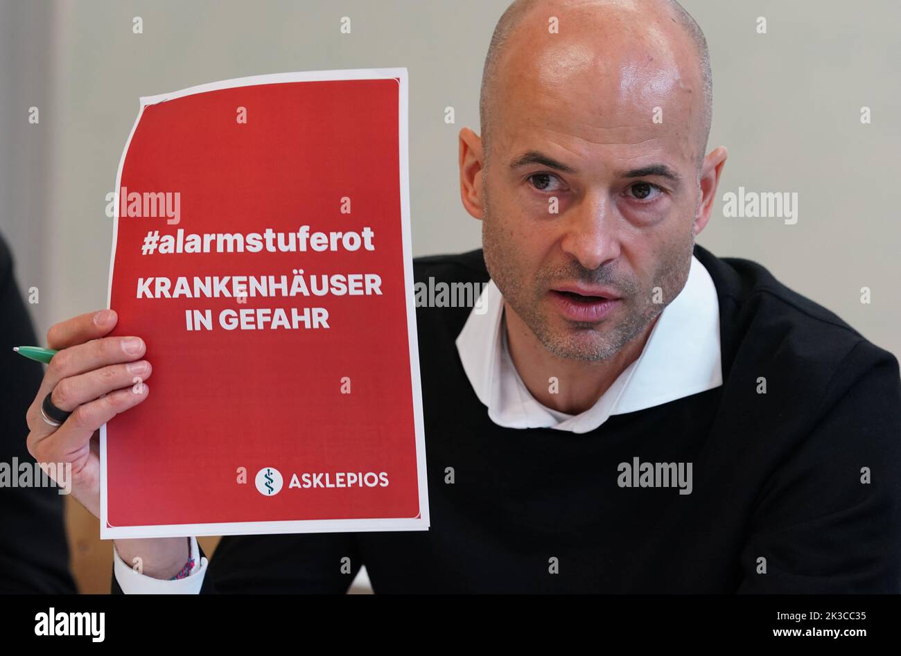 Hamburg, Germany. 26th Sep, 2022. Joachim Gemmel, Chairman of the Hamburg Hospital Association (HKG) and member of the Executive Board of Asklepios Kliniken GmbH & Co. KGaA, holds a red slip of paper with the inscription '#alarmstuferot. Hospitals at risk. Asklepios.' In a press conference, the Hamburg Hospital Association provided information on the economic situation of hospitals in Germany. Credit: Marcus Brandt/dpa/Alamy Live News Stock Photo