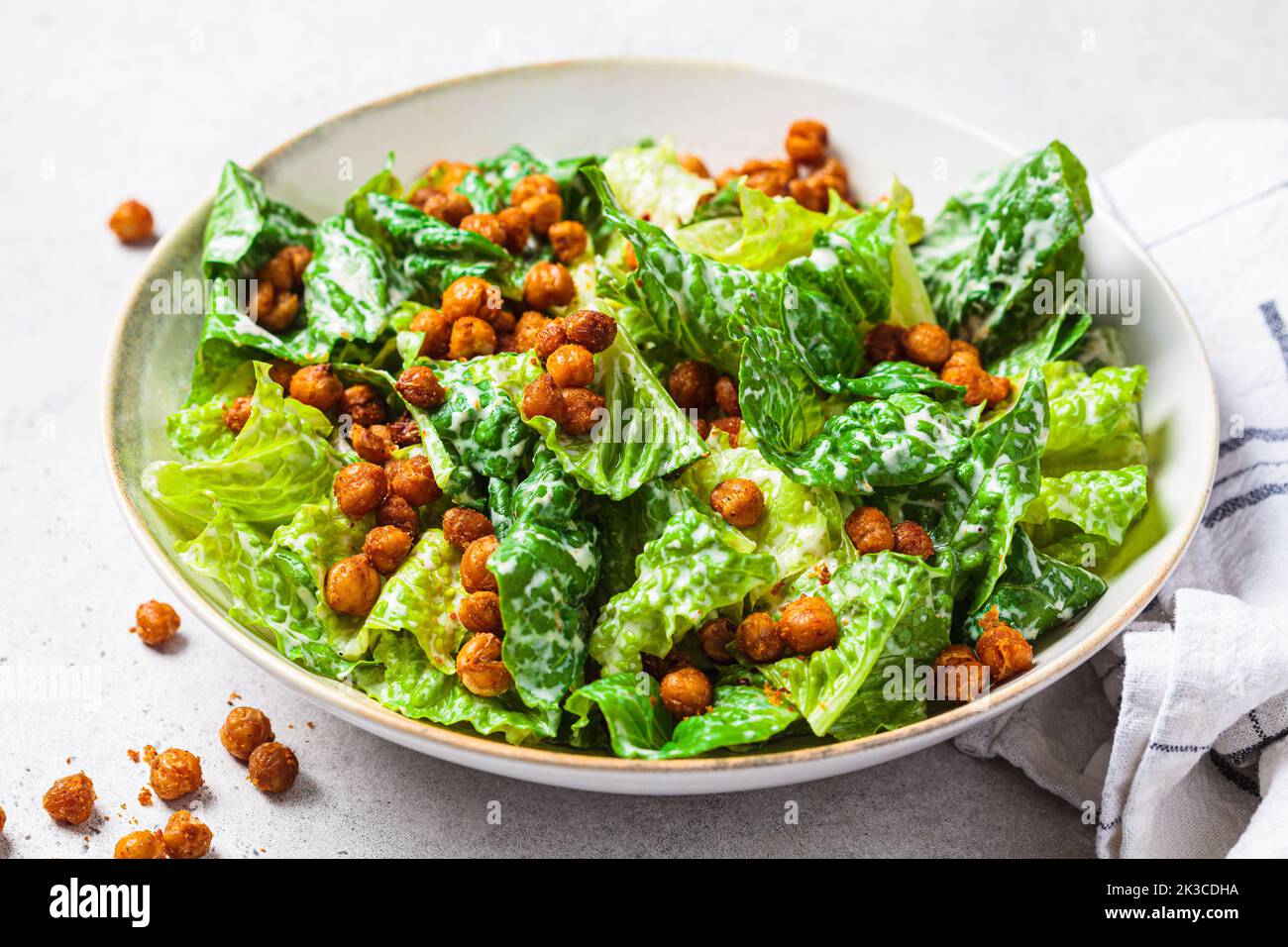 Vegan caesar salad with fried spicy chickpeas in a gray bowl. Plant based food concept. Stock Photo