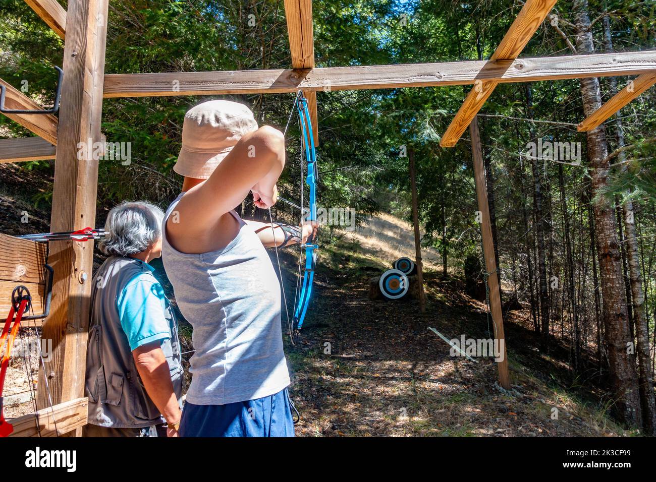 A boy trying archery, aiming an arrow at a target, bow drawn. Stock Photo