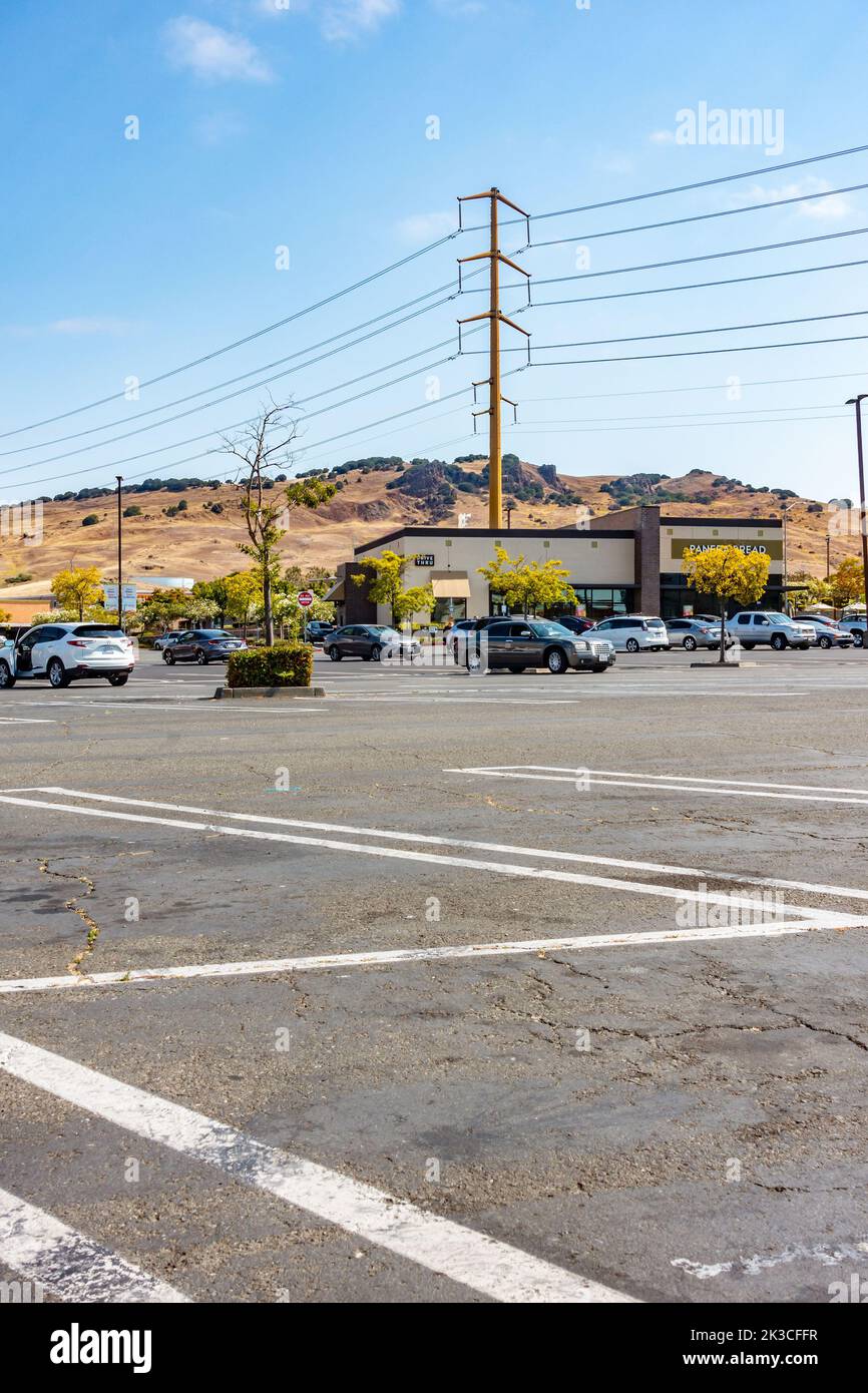 Overhead power cables held by pylons alongside a parking lot at a stip