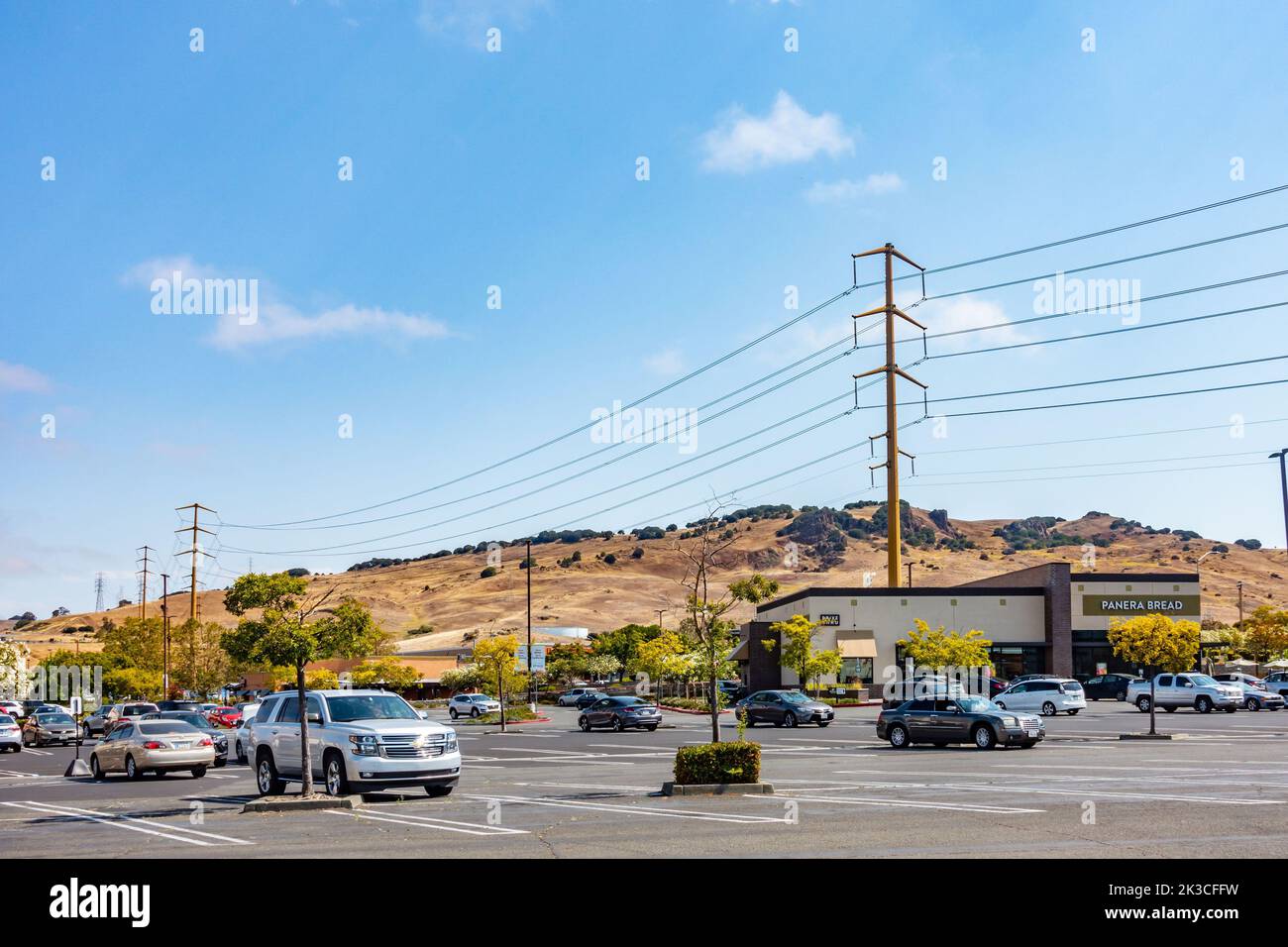 Overhead power cables held by pylons alongside a parking lot at a stip