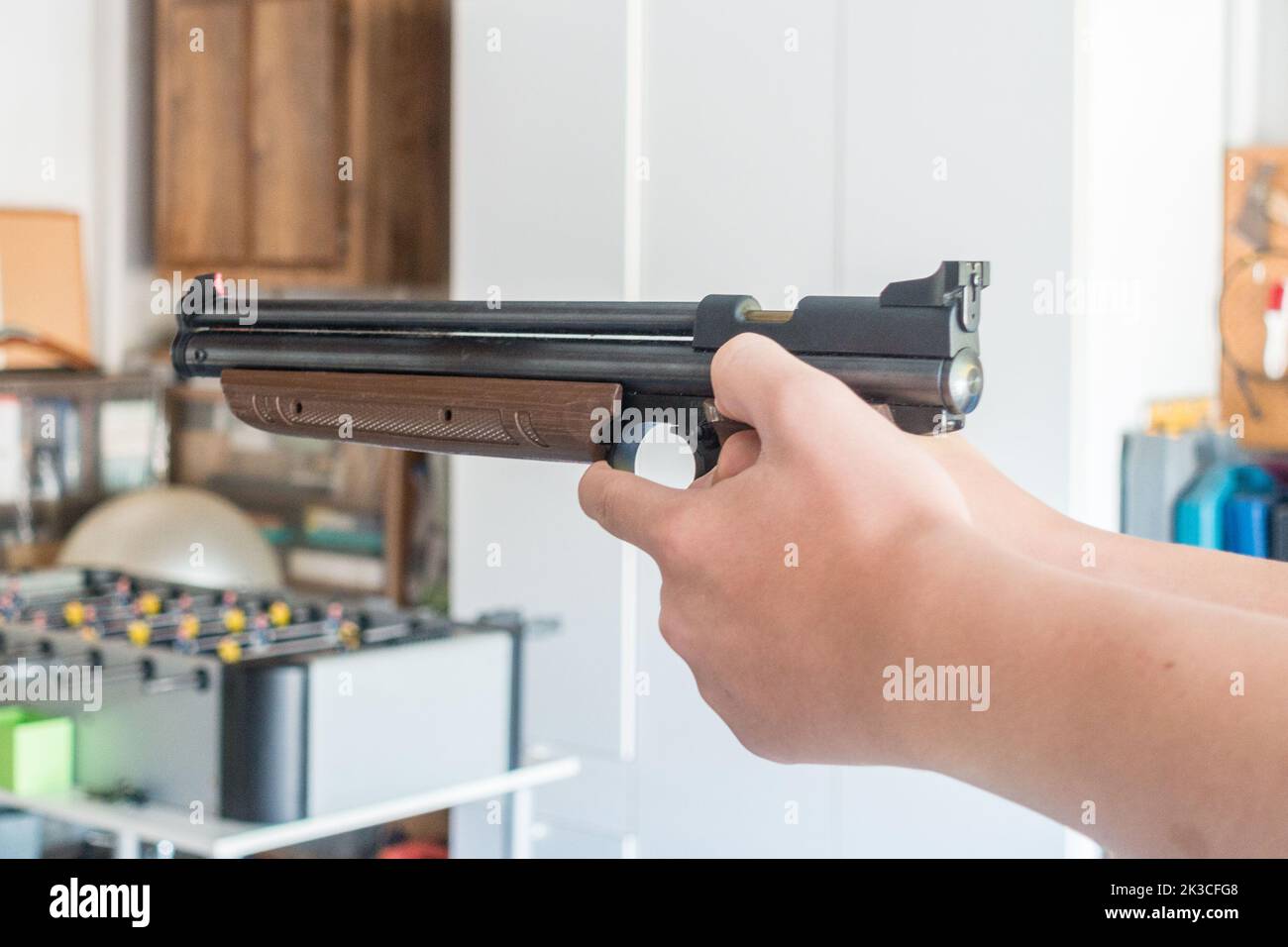 Close up view of a boy's hands holding and aiming an air pistol Stock Photo