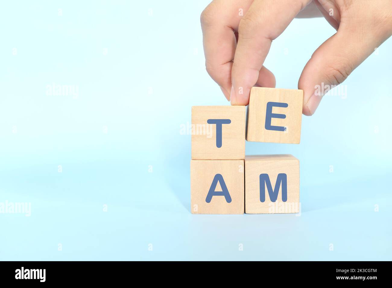 Teamwork and team building business concept. Hand putting together wooden blocks wood puzzle pieces in blue background. Stock Photo